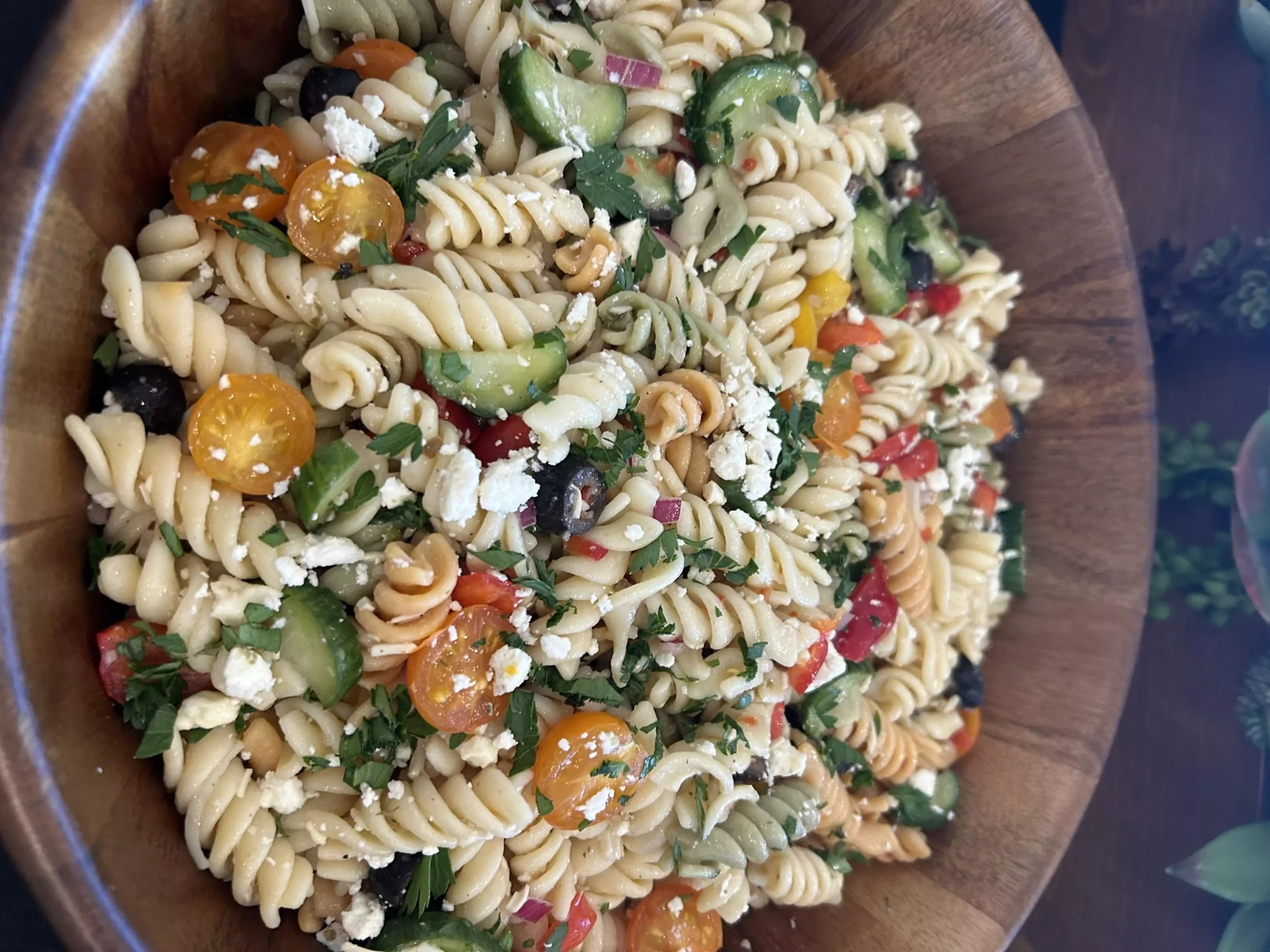 A bowl of pasta salad sits staged on a countertop.