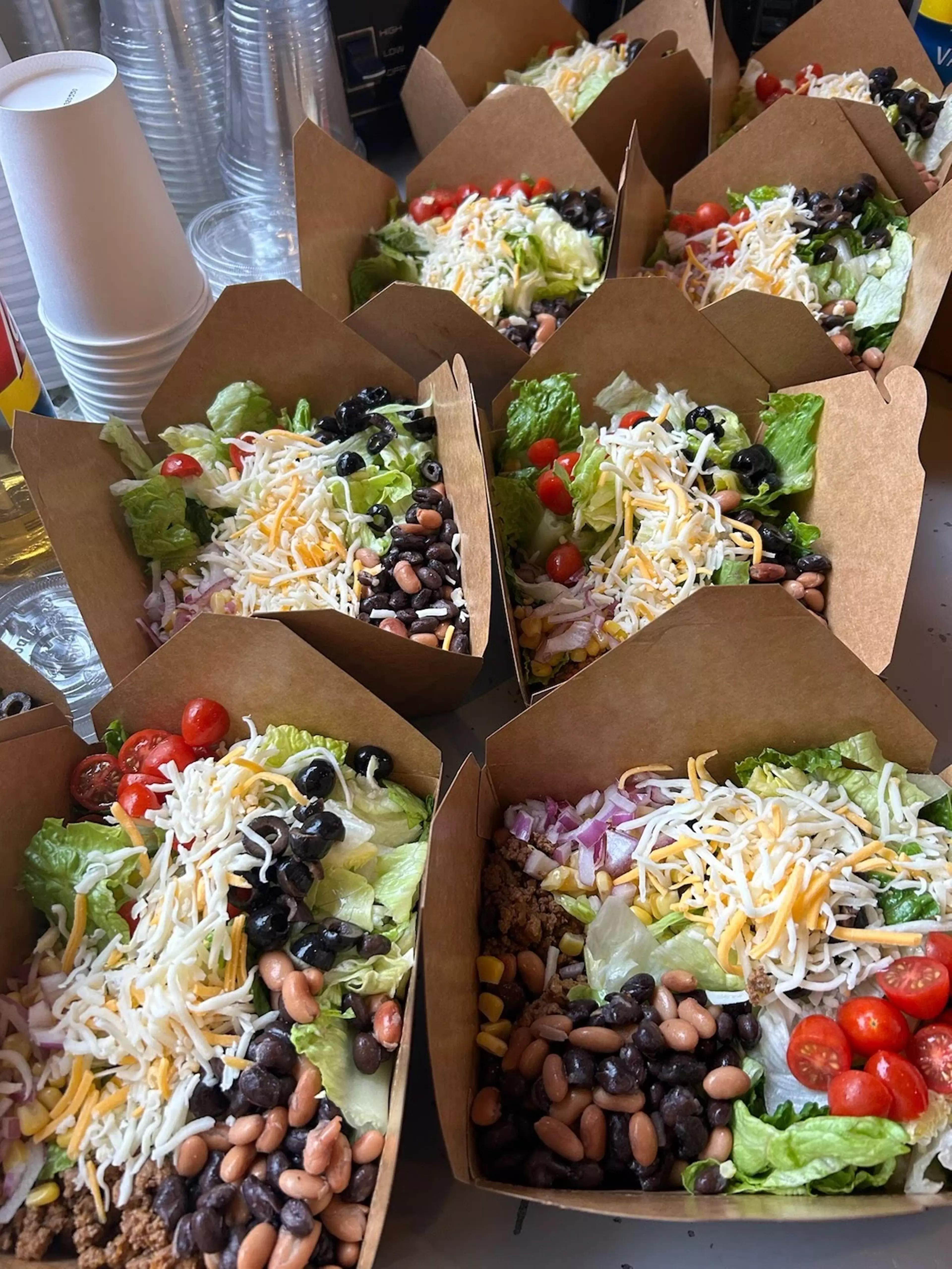 Several individually packaged to-go salads are arranged on a countertop.