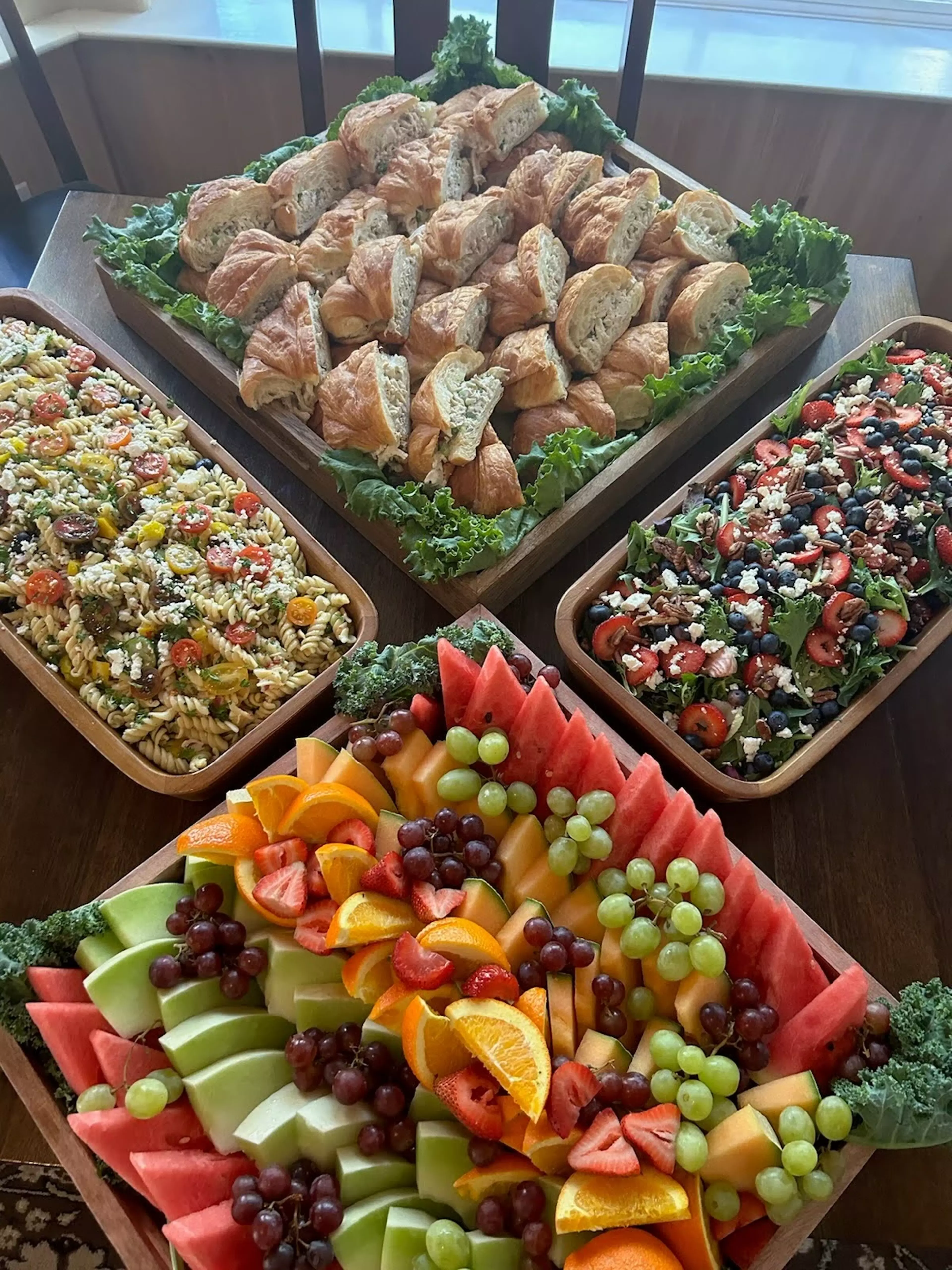 Four baskets full of bread, pasta salad, fruit, and salad arranged in a diamond shape.